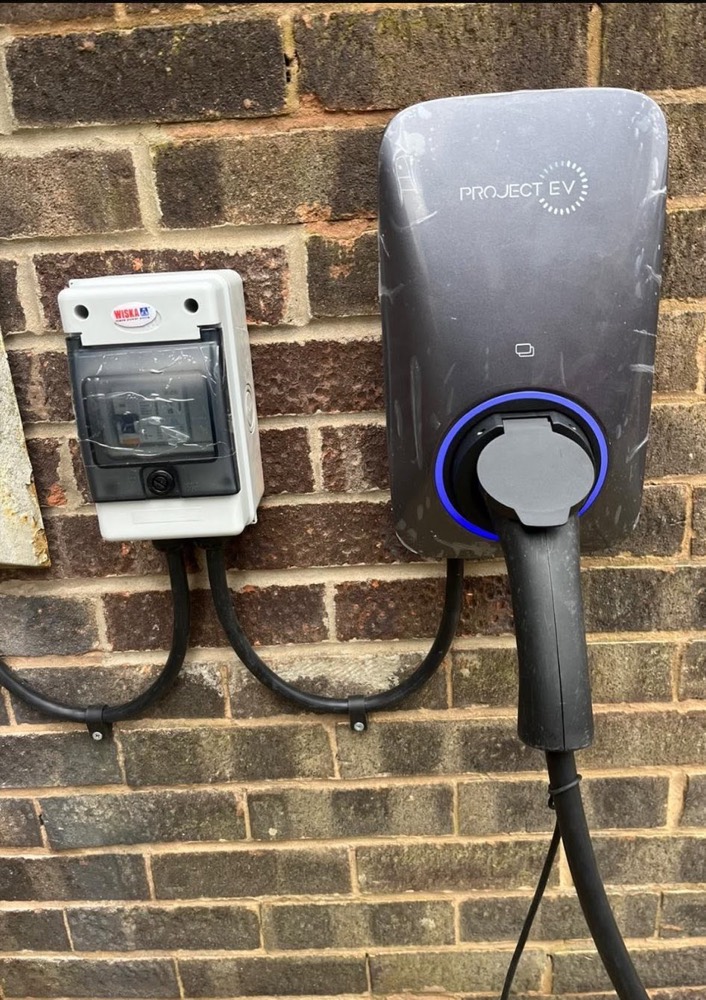 Wall-mounted smart EV charge point installation on a stone house