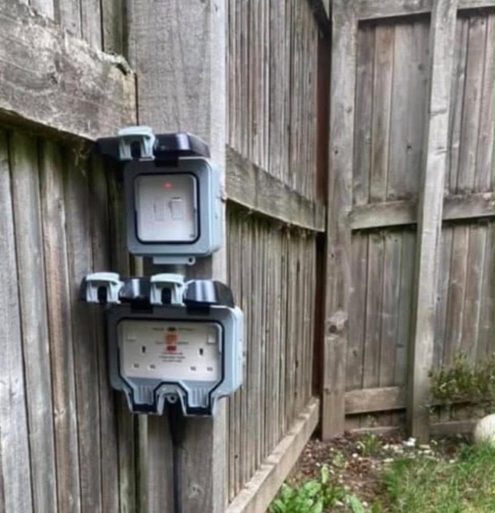 Weatherproof outdoor sockets and switch installed on a garden fence post