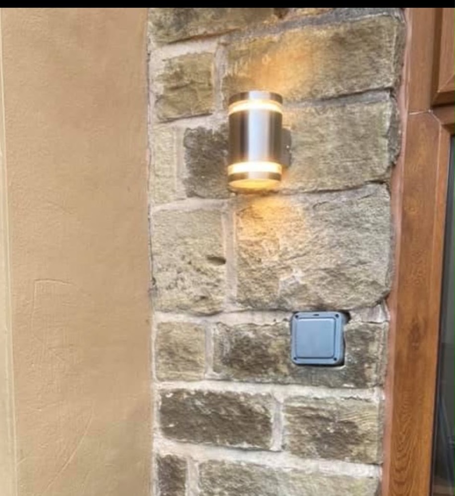 Stainless steel up-and-down wall light on a Yorkshire stone wall